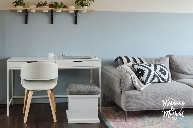 white office desk and chair near gray couch on blue wall