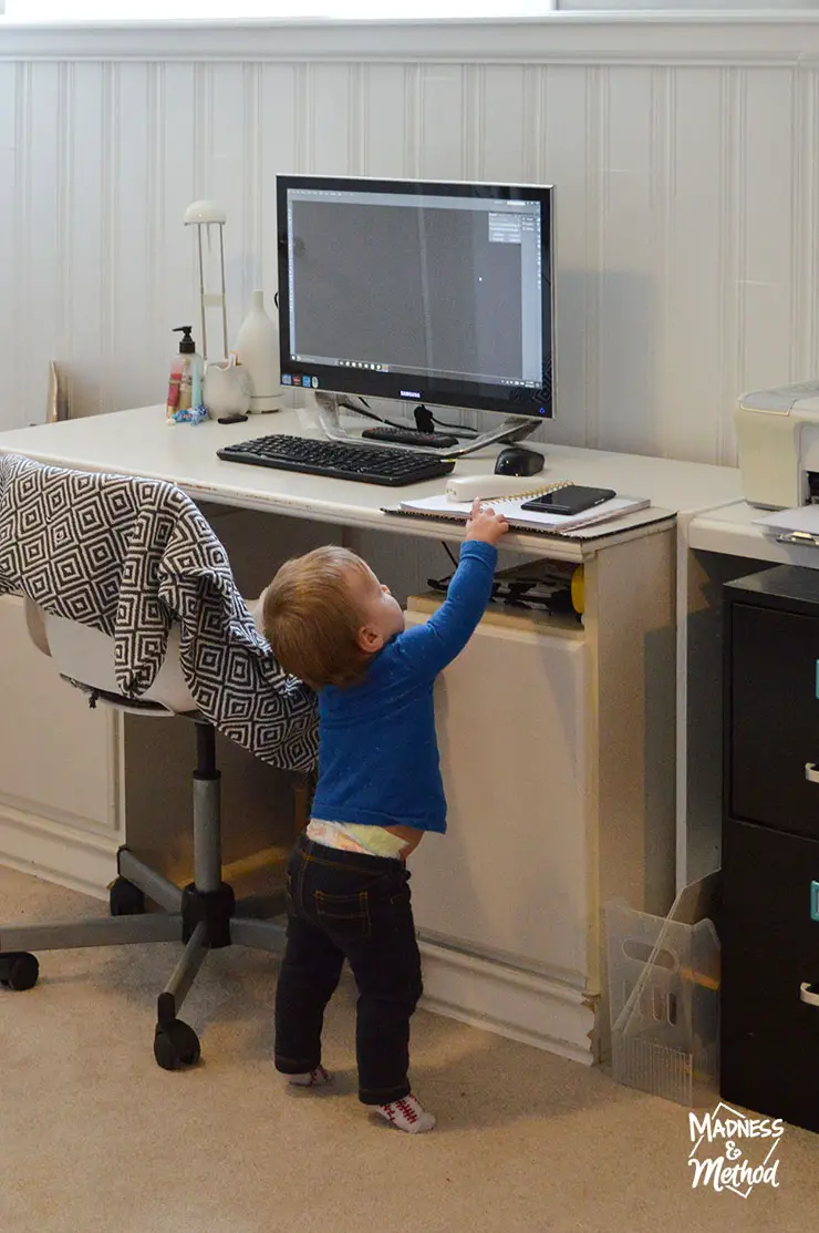 baby in blue shirt reaching for office desk