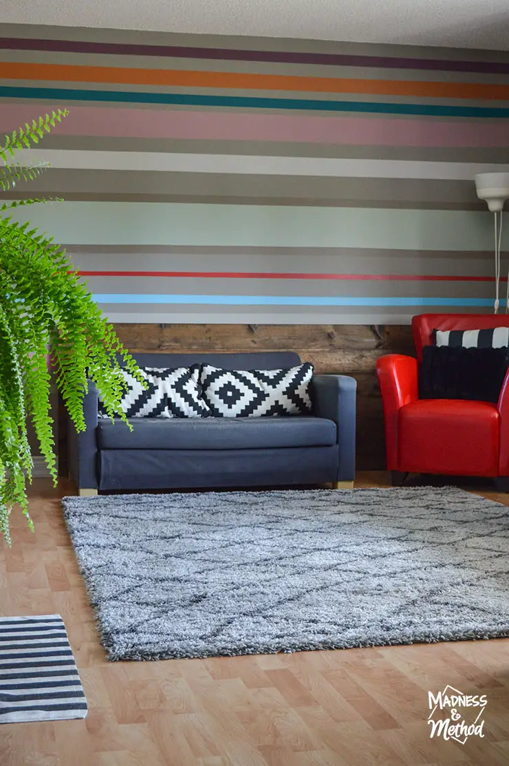 striped accent wall with gray sofa shag gray rug and red chair