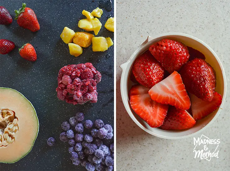 fruit on black cutting board and cut strawberries in container