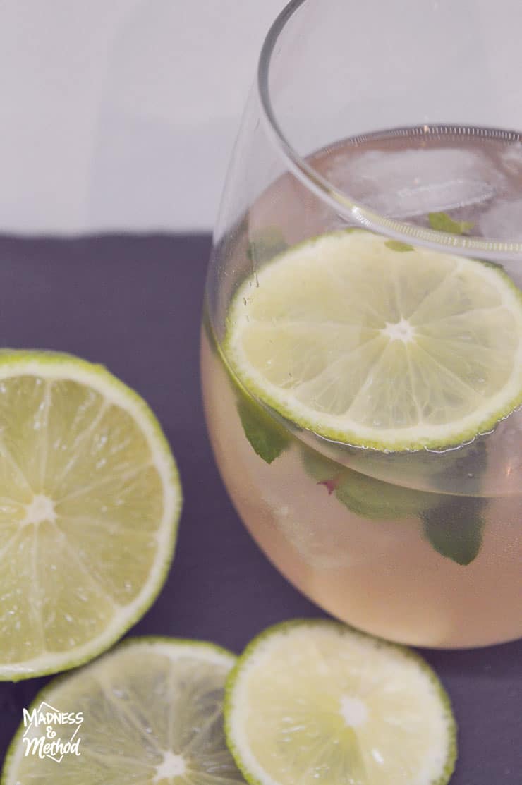 stemless wine glass with clear pink liquid and lime wedges