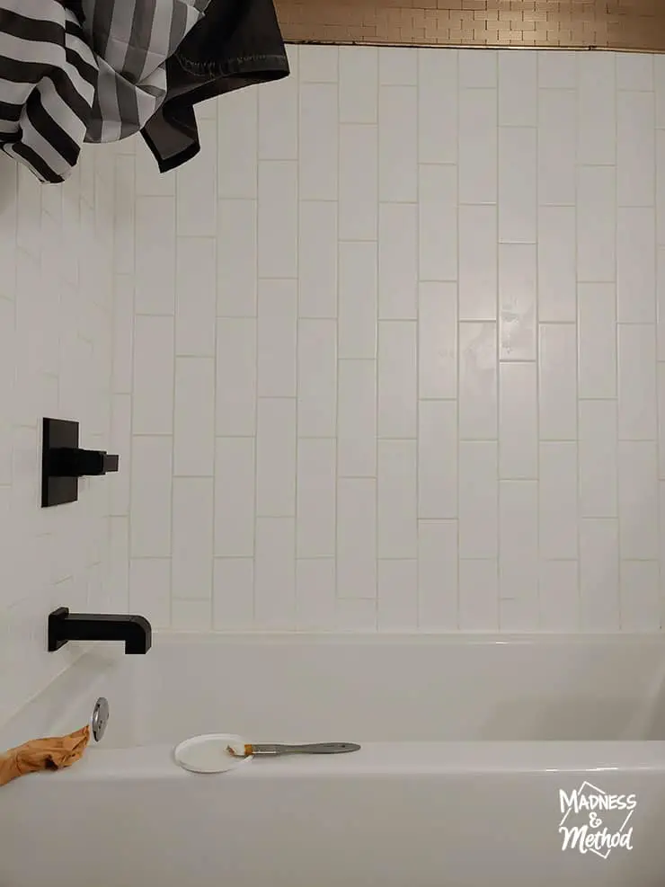 long white subway tiles in tub surround with black faucets