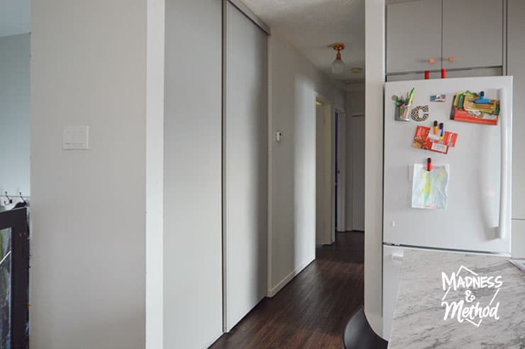 hallway with white walls gray closet door and dark floors