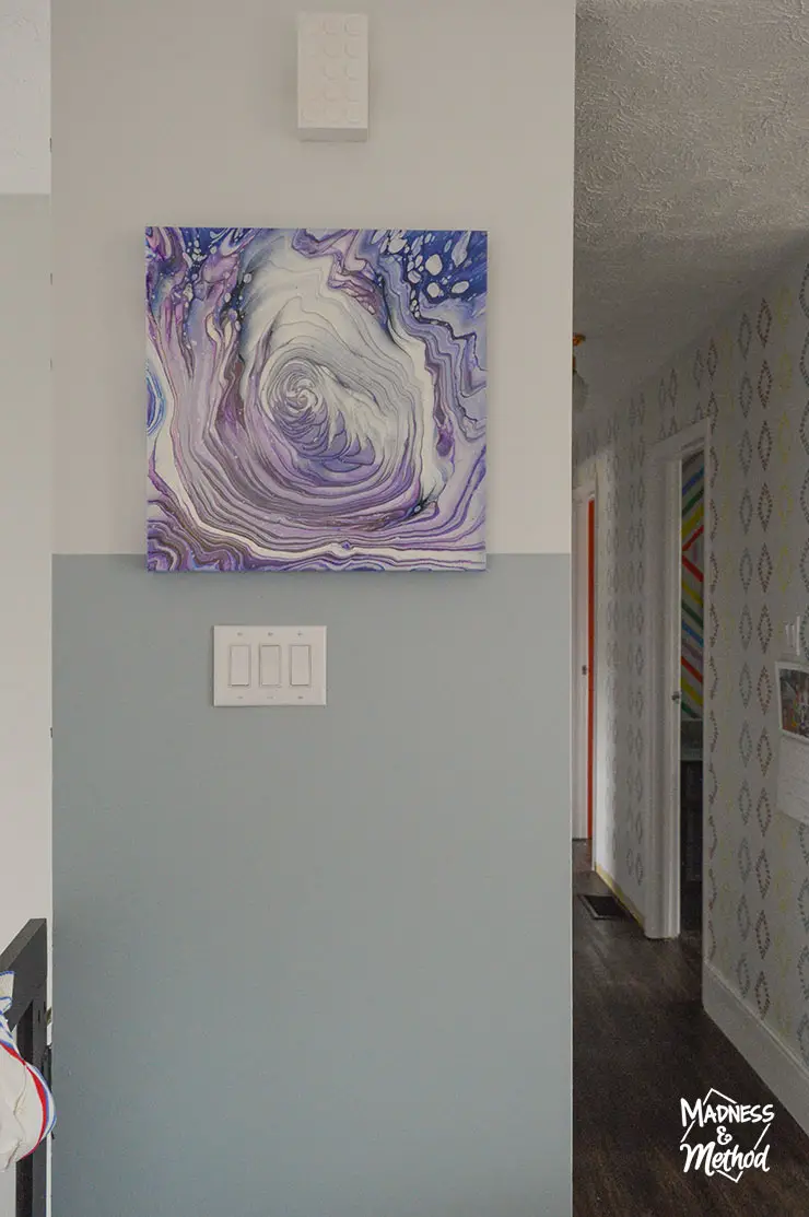 purple painting hung in blue hallway