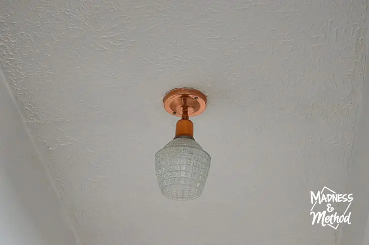 copper light fixture on white textured ceiling