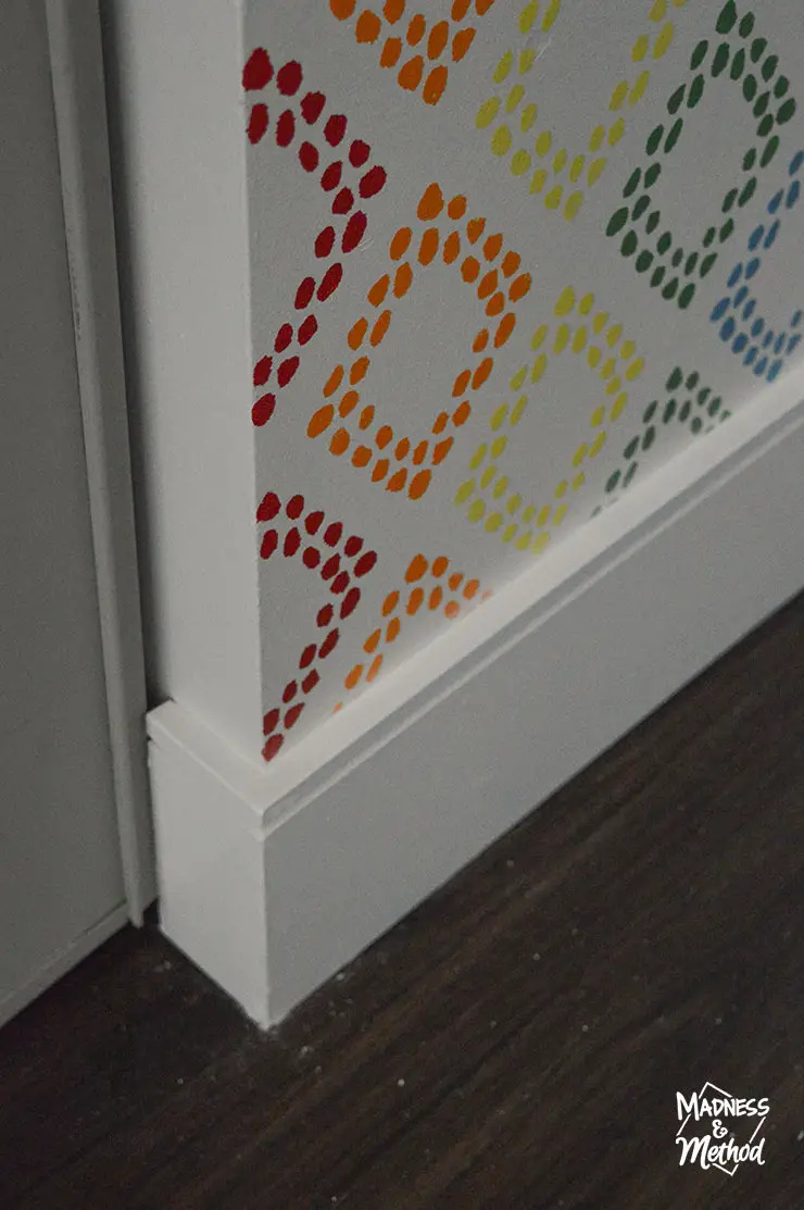white baseboards and dark vinyl floors with rainbow stencil