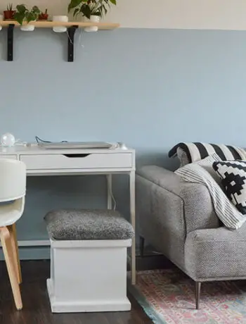 white office desk and chair near gray couch on blue wall