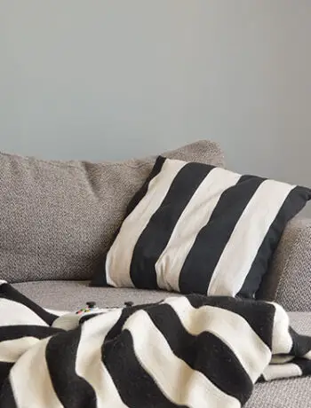 black white stripe pillow and blanket on gray couch