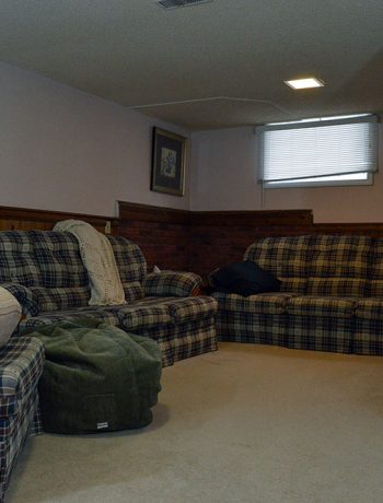 My basement is definitely "country". Think plaid and dark wood paneling, and that pretty much describes this space. You know what style I am not? Country! But, let's look at pictures of the basement anyways, along with my lovely little comments of issues I would change...