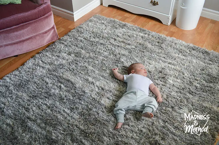 baby on shag gray rug with pink chair nearby