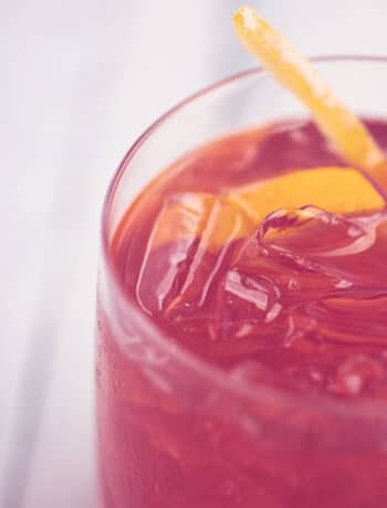 red drink with ice and lemon peel
