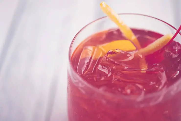 red drink with ice and lemon peel