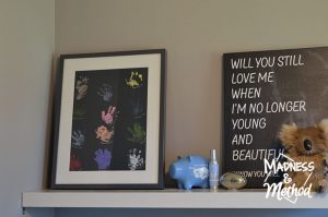 Baby handprint art in a frame, sitting on a shelf