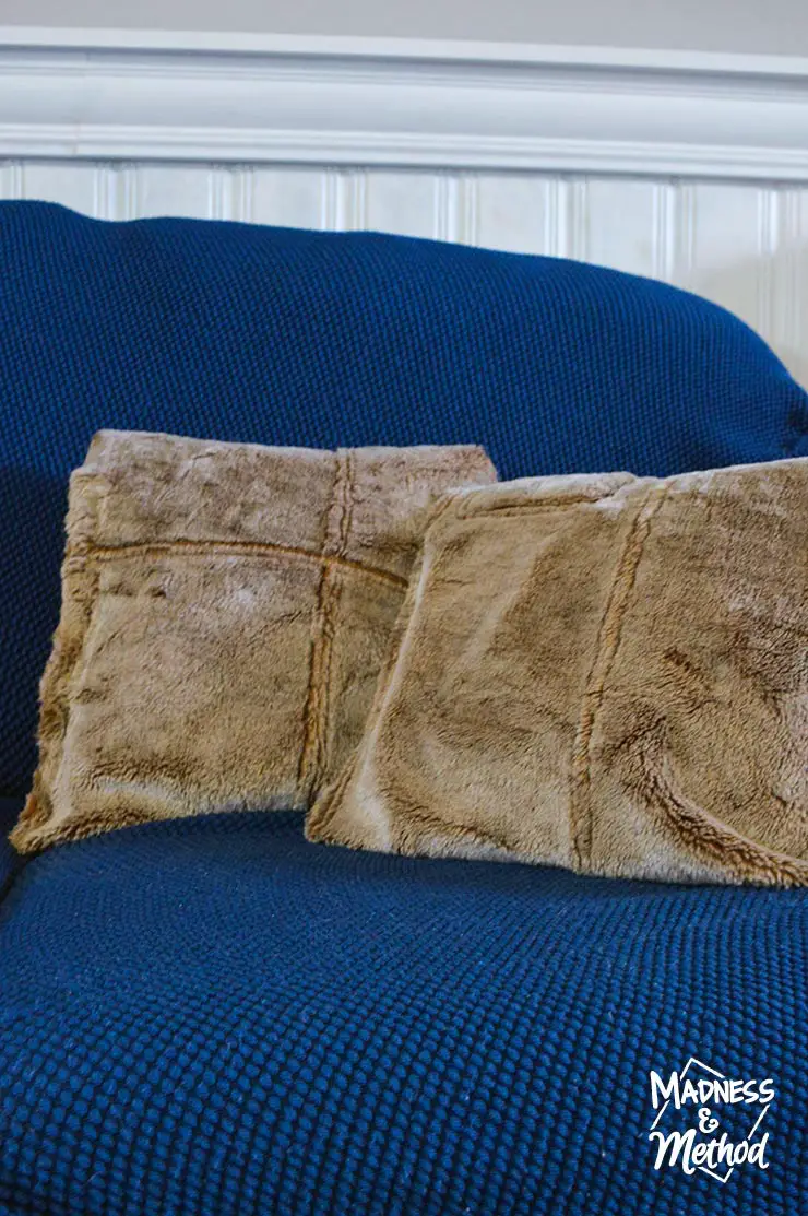 two beige faux fur pillows on blue couch