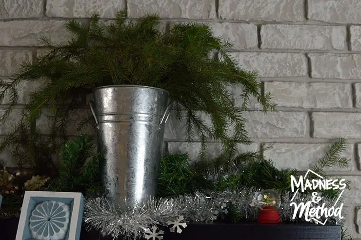 bucket with greenery on holiday mantel