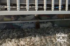 baby clothes in bins under crib