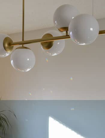 modern gold and globe light fixture against walls