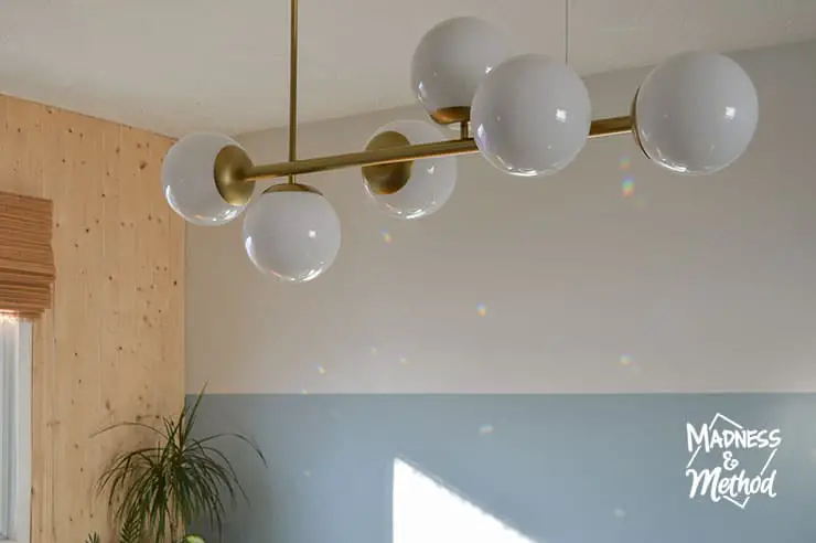 modern gold and globe light fixture against walls