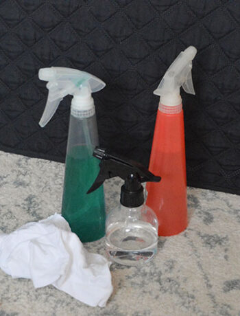 three spray bottles near rag on rug