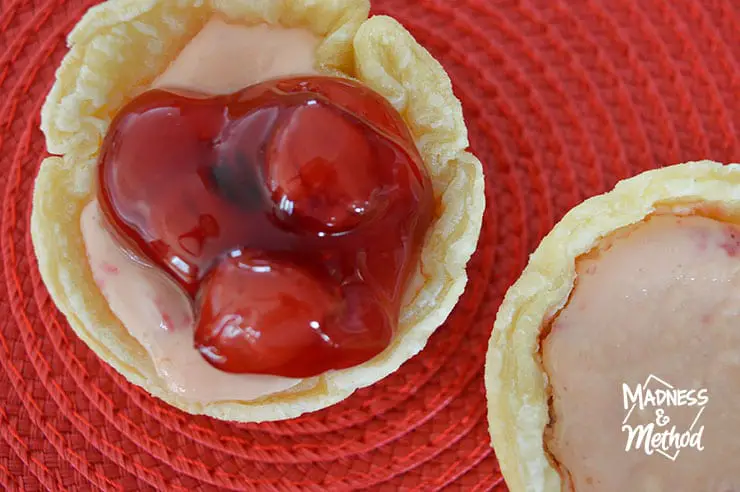 muffin sized cherry cheesecake tart on red background