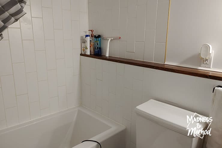 white subway tile tub surround with wood ledge