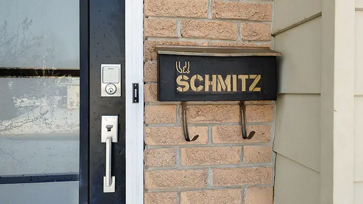 black mailbox on beige bricks near black and glass door