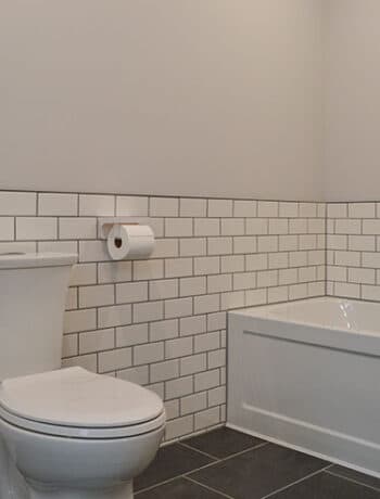 white subway tile behind toilet and tub