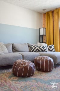 gray sofa brown leather poofs blue walls yellow curtains