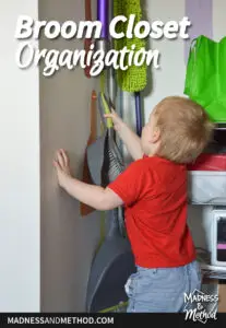 toddler in red shirt grabbing dustpan in closet