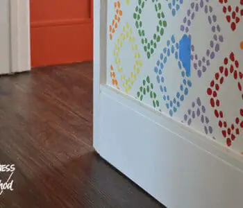 white baseboards against dark floors and rainbow walls