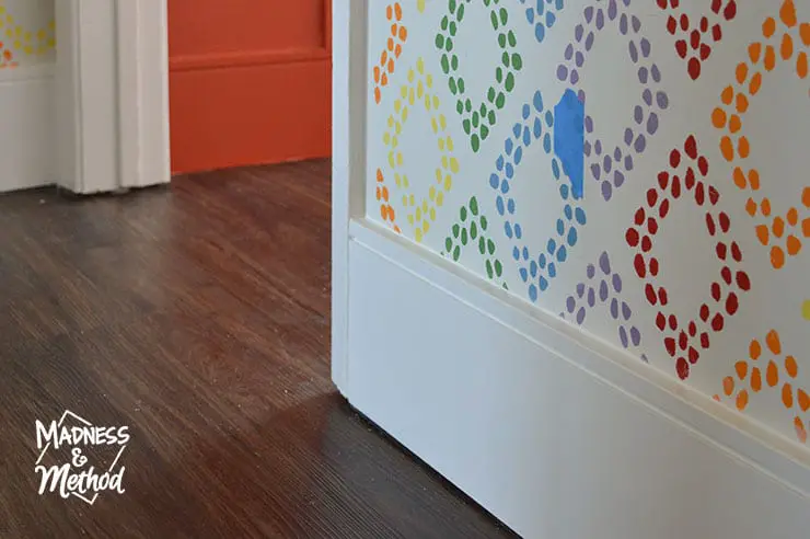 white baseboards against dark floors and rainbow walls