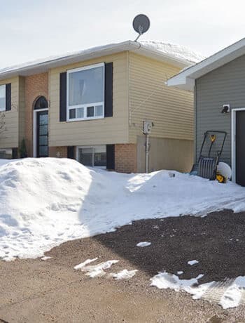 raised ranch house with snow and detached garage