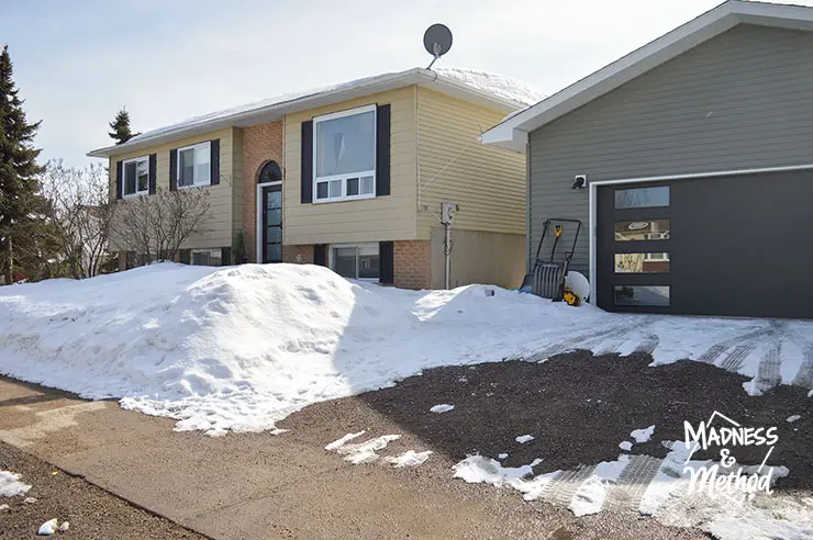 raised ranch house with snow and detached garage